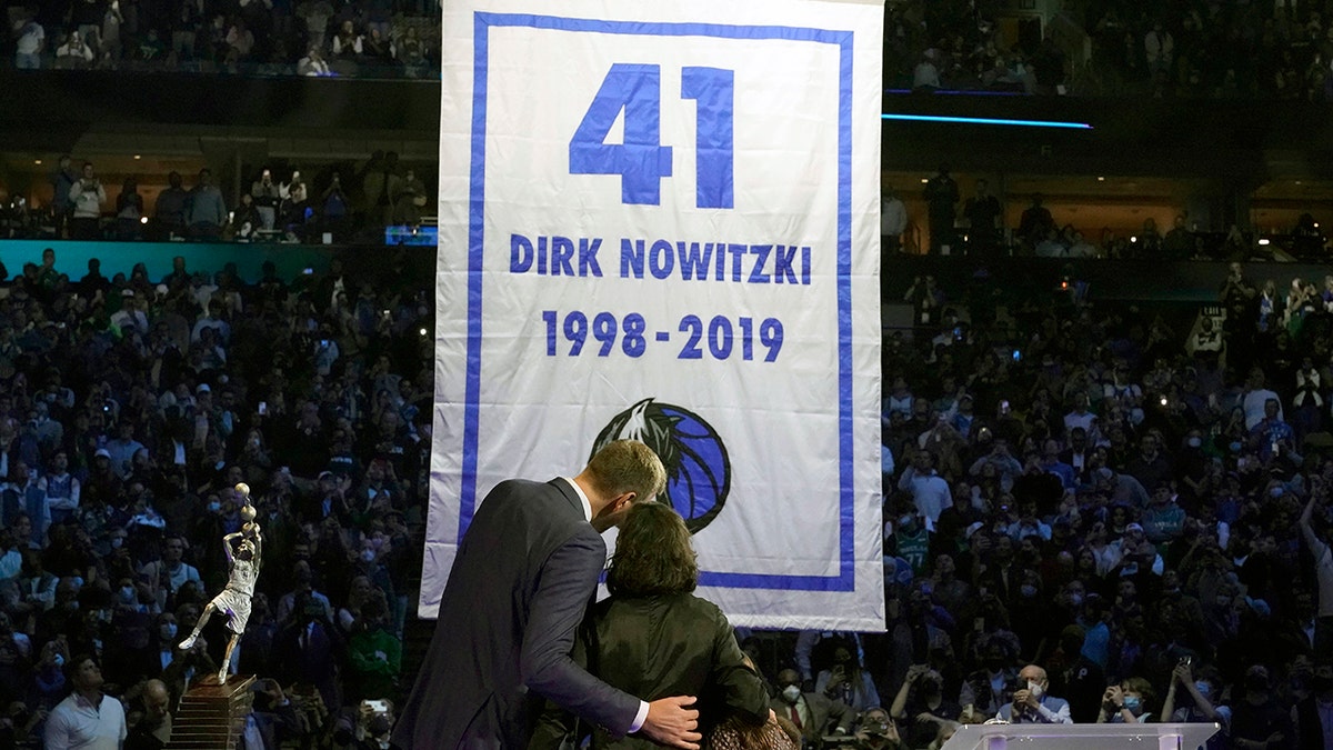 Former Dallas Mavericks Dirk Nowitzki, left, and his wife Jessica Olsson watch a banner being raised during a number retirement ceremony for Nowitzki after an NBA basketball game between the Golden State Warriors and Dallas Mavericks in Dallas, Wednesday, Jan. 5, 2022.