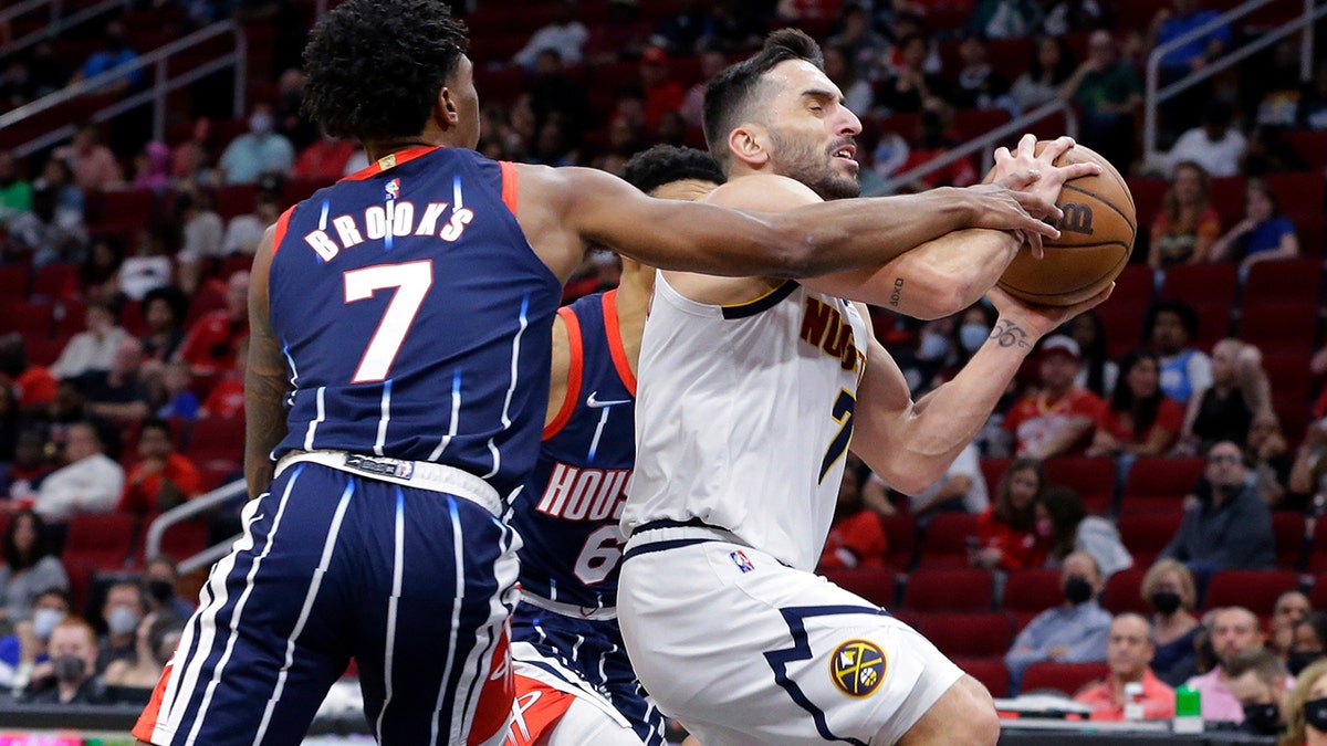 Houston Rockets guard Armoni Brooks, left, fouls Denver Nuggets guard Facundo Campazzo during the first half of an NBA basketball game Saturday, Jan. 1, 2022, in Houston.