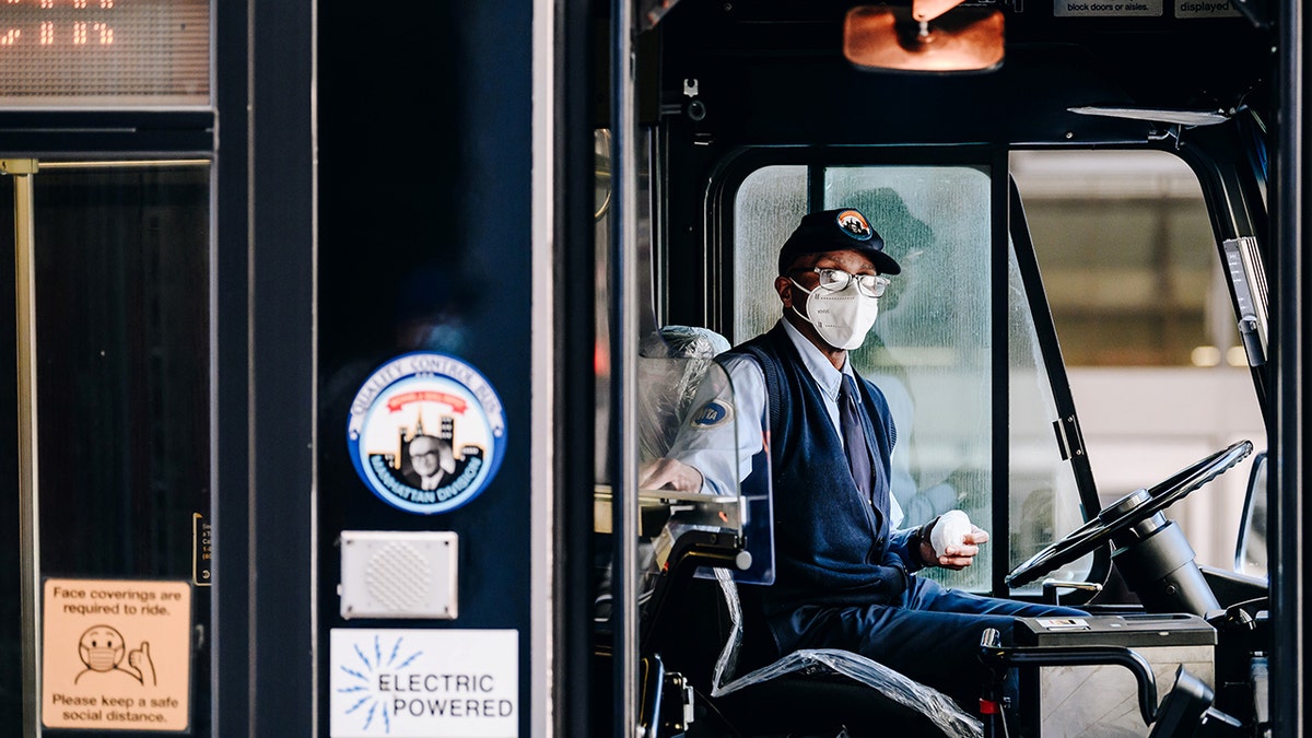 An MTA bus driver wears a protective mask while picking up passengers at a bus stop on 8th Avenue in New York on April 13, 2021. 