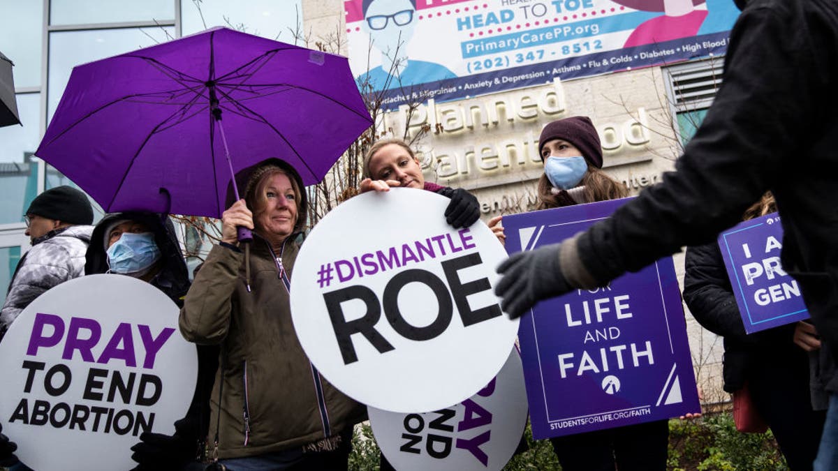 Anti-abortion activist pass out signs during a protest outside a Planned Parenthood clinic on Jan. 20, 2022 in Washington, DC. (Photo by Drew Angerer/Getty Images)