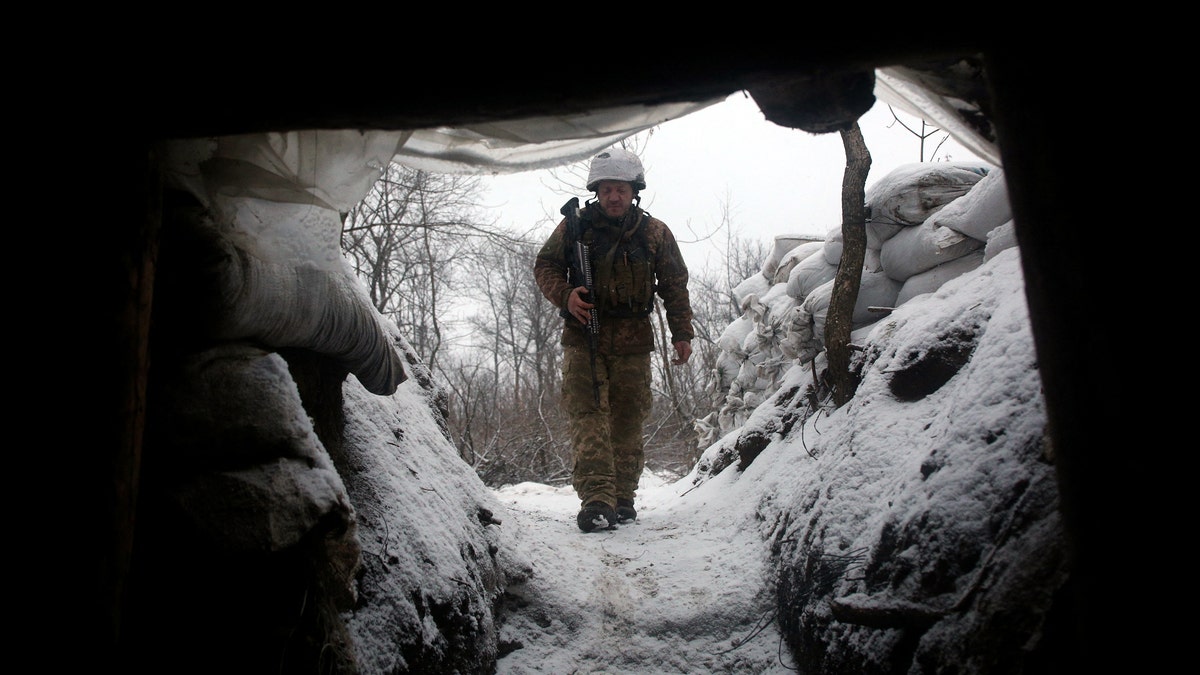 Ukrainian Military Forces serviceman walks along a snow covered trench on the frontline with the Russia-backed separatists near Zolote village, Ukraine