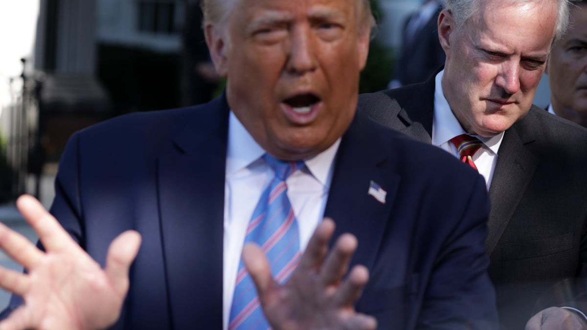 U.S. President Donald Trump speaks as White House Chief of Staff Mark Meadows (R) listens.