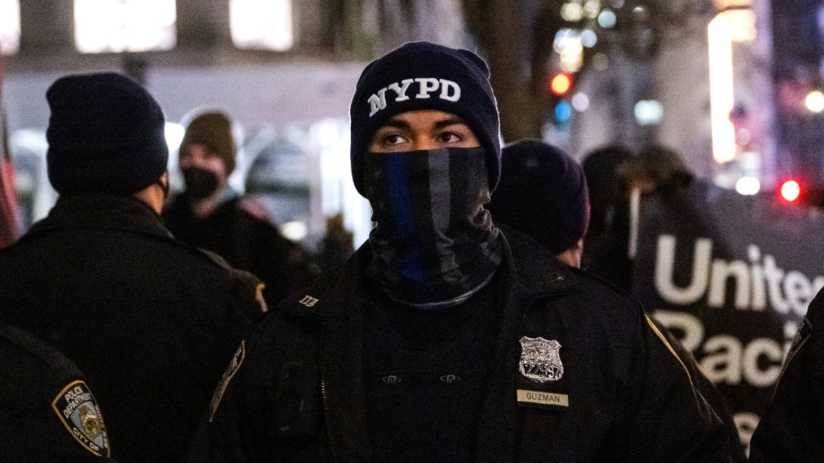 A member of the NYPD wearing a 'back the blue' face mask stands between supporters of former President Donald Trump and counter protestors during a candlelight vigil outside of St. Patrick’s Cathedral on January 6, 2022 in New York City. One year ago, supporters of President Donald Trump attacked the U.S. Capitol Building in an attempt to disrupt a congressional vote to confirm the electoral college win for Joe Biden. (Photo by Alexi Rosenfeld/Getty Images)