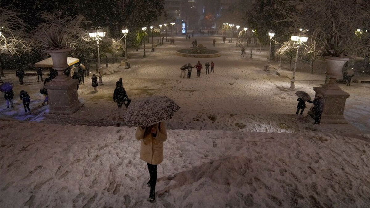 People walk on the snow-covered Syntagma square during a snowstorm in Athens, Greece, Monday, Jan. 24, 2022. 