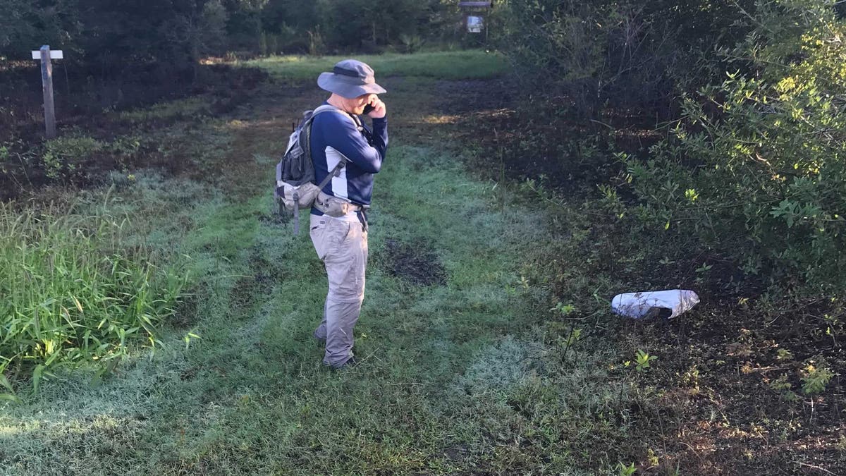 A North Port, Florida, detective makes a phone call from the entrance of Myakkahatchee Creek Environmental Park on Oct. 20, 2021.