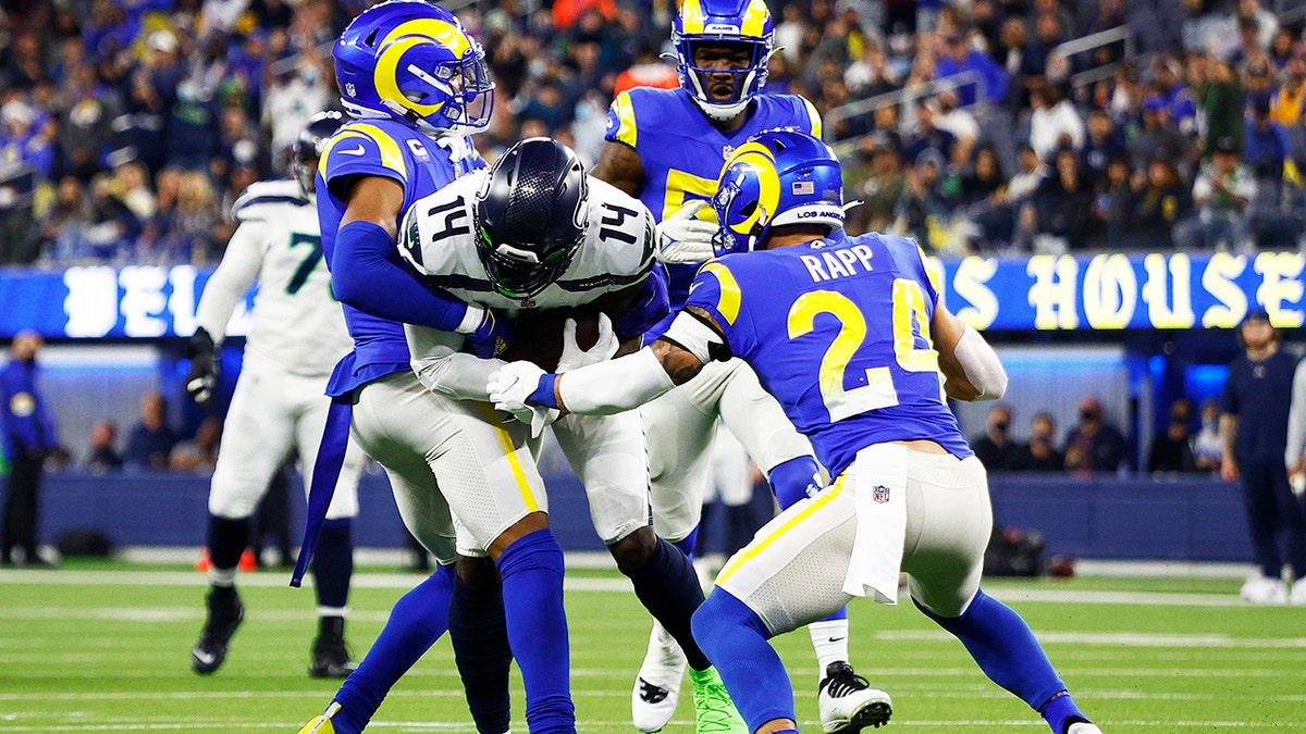 DK Metcalf of the Seattle Seahawks is tackled by Taylor Rapp and Jalen Ramsey of the Los Angeles Rams at SoFi Stadium on Dec. 21, 2021, in Inglewood, California.