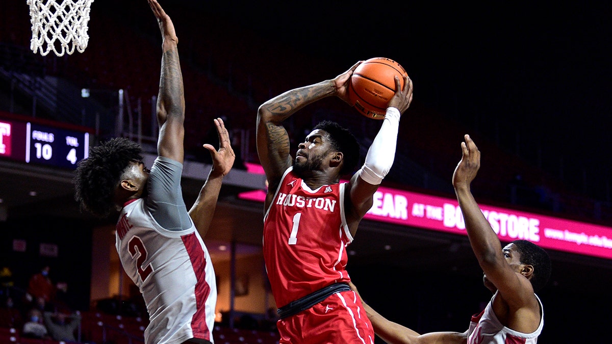 Houston's Jamal Shead (1) shoots past the defense of Temple's Jahlil White (2) and Hysier Miller during the first half of an NCAA college basketball game, Sunday, Jan. 2, 2022, in Philadelphia.