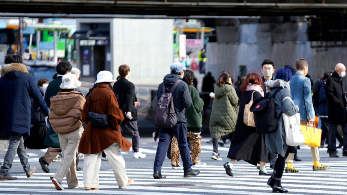 People wearing protective masks to help curb the spread of the coronavirus walk along a pedestrian crossing Friday, Jan. 21, 2022, in Tokyo. ?