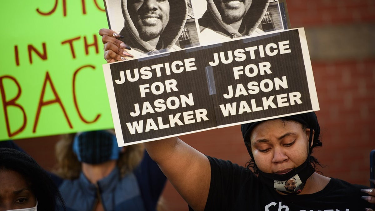 Pandora Harrington holds up a sign with an image of Jason Walker during a demonstration in front of the Fayetteville Police Department on Sunday.