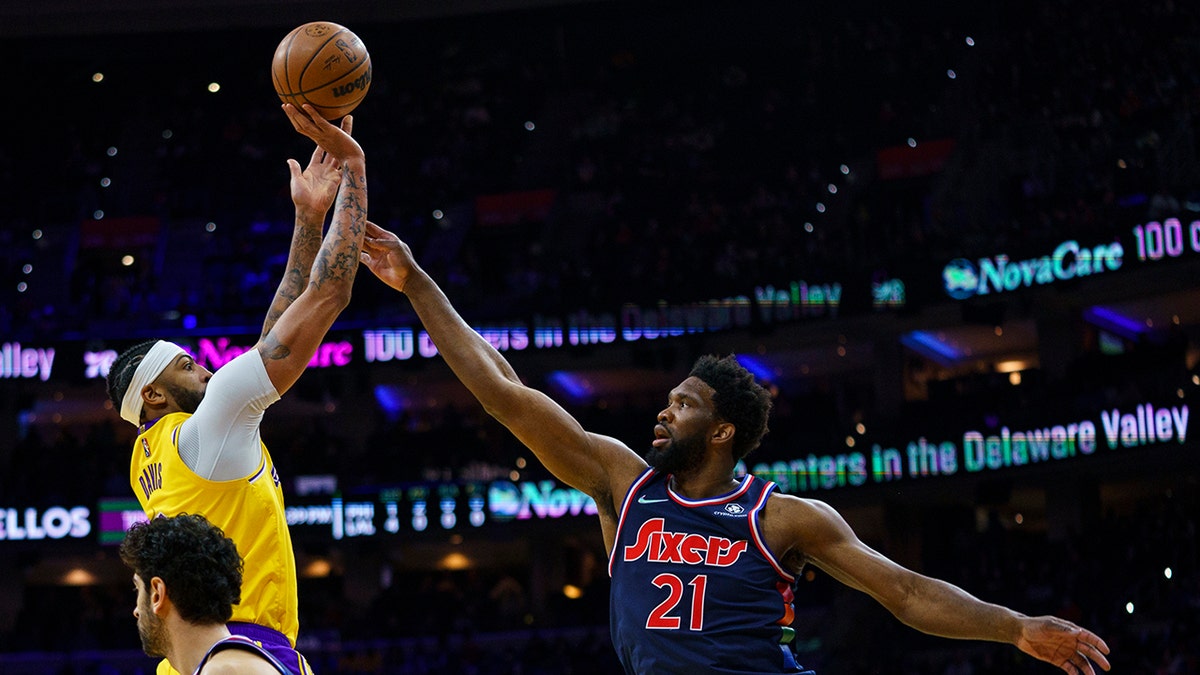 Los Angeles Lakers' Anthony Davis, left, shoots the ball with Philadelphia 76ers' Joel Embiid, right, defending during the first half of an NBA basketball game, Thursday, Jan. 27, 2022, in Philadelphia.