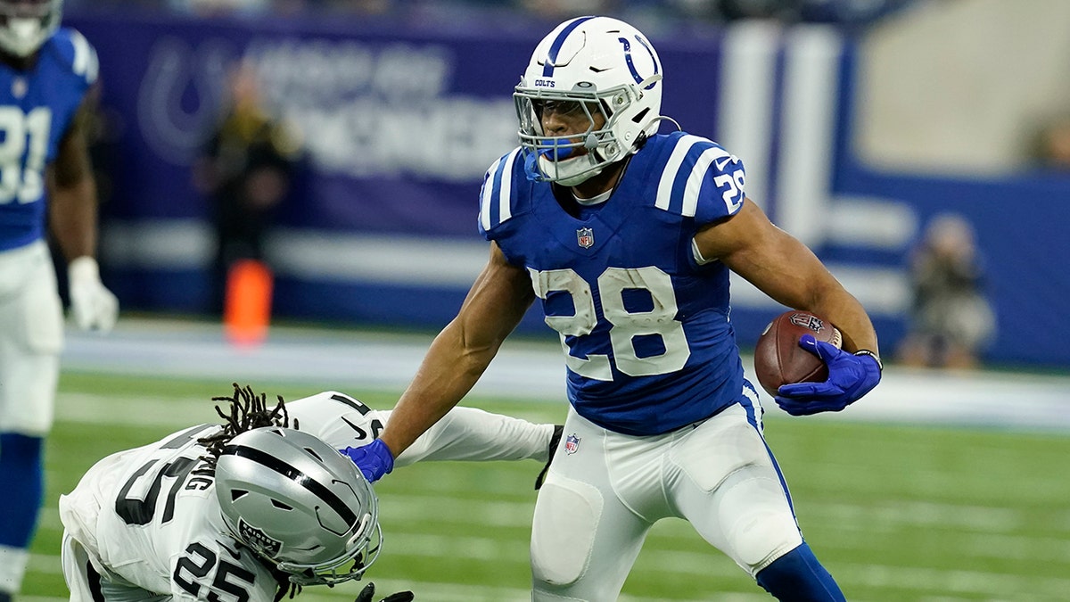 Indianapolis Colts running back Jonathan Taylor (28) tries to break a tackle by Las Vegas Raiders free safety Trevon Moehrig (25) during the first half of an NFL football game, Sunday, Jan. 2, 2022, in Indianapolis. 