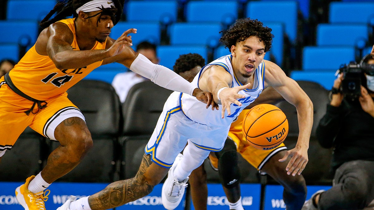 UCLA guard Jules Bernard, right, dives in an attempt to reach the ball next to Long Beach State guard Colin Slater during the second half of an NCAA college basketball game Thursday, Jan. 6, 2022, in Los Angeles. UCLA won 96-78.
