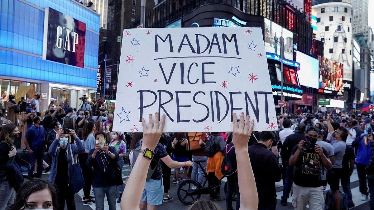 A person holds a sign as others celebrate after media announced that Democratic U.S. presidential nominee Joe Biden has won the 2020 U.S. presidential election, on Times Square in New York City, Nov. 7, 2020. 