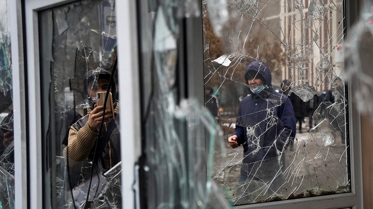 A man takes a photo of windows of a police kiosk damaged by demonstrators during a protest in Almaty, Kazakhstan, Wednesday, Jan. 5, 2022. (AP Photo/Vladimir Tretyakov)