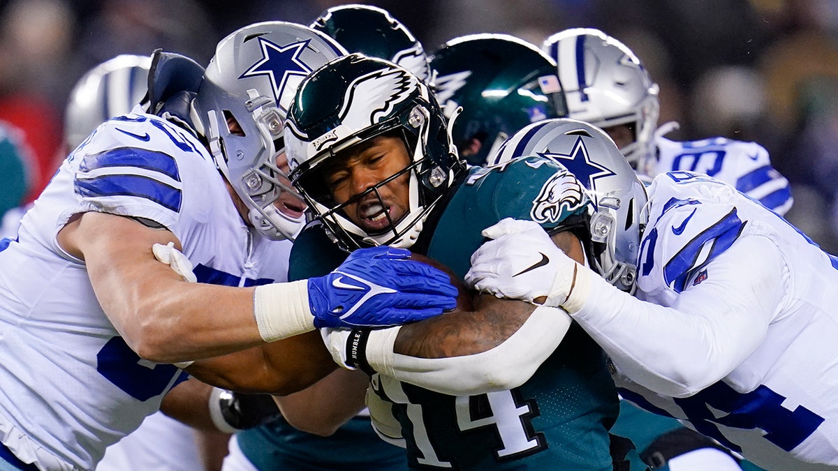 Philadelphia Eagles running back Kenneth Gainwell (14) runs with the ball as Dallas Cowboys outside linebacker Leighton Vander Esch, left, and defensive end Randy Gregory, right, try to stop him during the first half of an NFL football game, Saturday, Jan. 8, 2022, in Philadelphia.