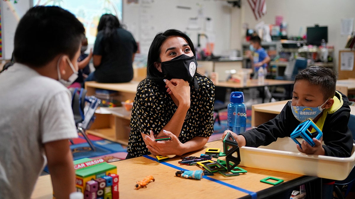Teacher Juliana Urtubey, center, works with Brian Avilas, left, and Jesus Calderon Lopez, right, in a class at Kermit R Booker Sr Elementary School Wednesday, May 5, 2021, in Las Vegas. 