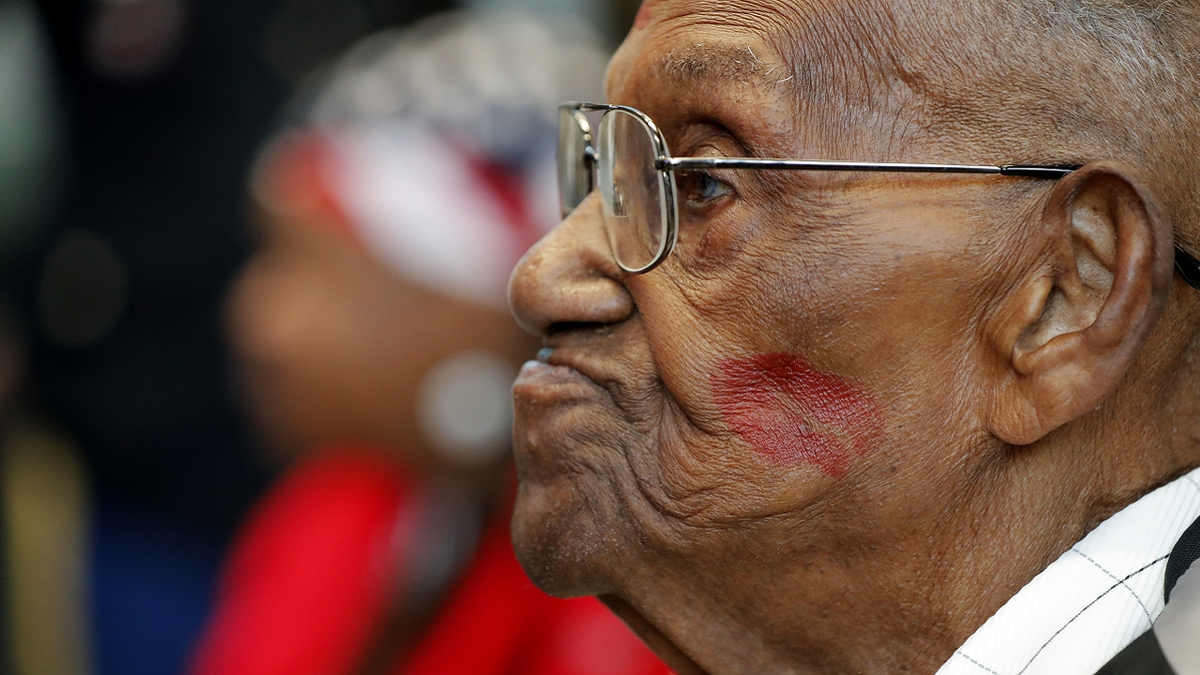 World War II veteran Lawrence Brooks sports a lipstick kiss on his cheek, planted by a member of the singing group Victory Belles, during his 110th birthday celebration.
