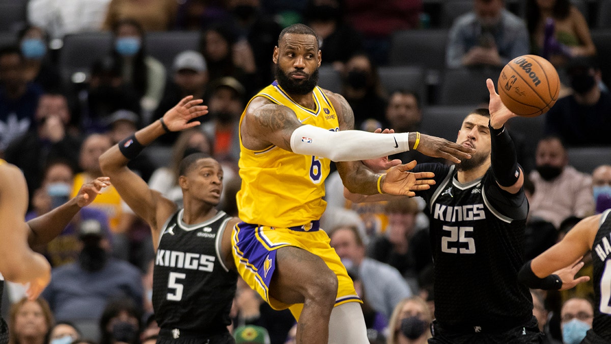 Los Angeles Lakers forward LeBron James (6) passes off while defended by Sacramento Kings guard De'Aaron Fox (5) and center Alex Len (25) in the second half of an NBA basketball game in Sacramento, Calif., Wednesday, Jan. 12, 2022. The Kings won 125-116.