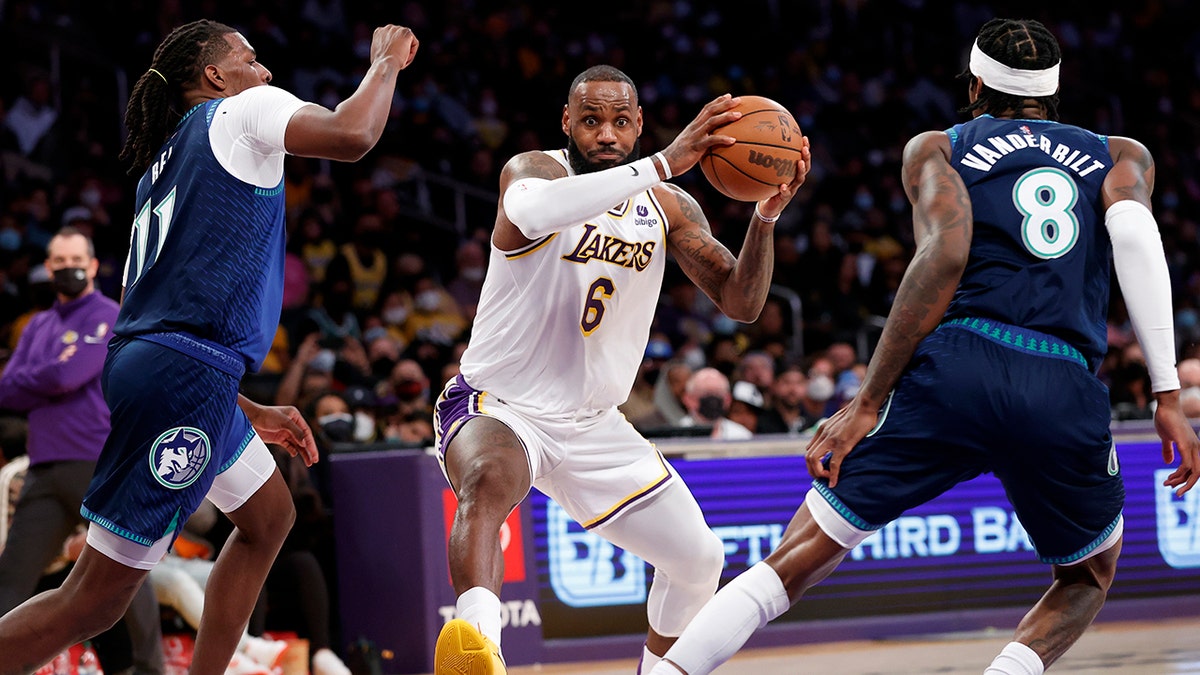 Los Angeles Lakers forward LeBron James (6) drives between Minnesota Timberwolves center Naz Reid (11) and Jarred Vanderbilt (8) during the first half of an NBA basketball game in Los Angeles, Sunday, Jan. 2, 2022.