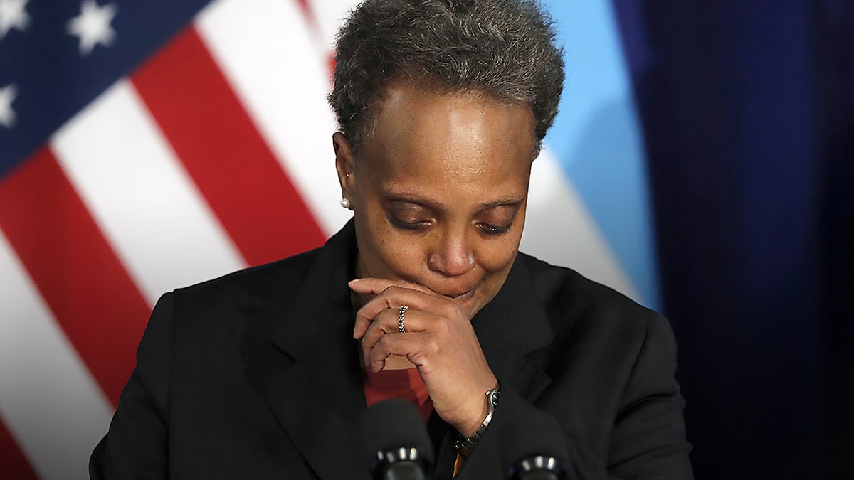 Chicago Mayor Lori Lightfoot wipes her mouth in front of an American flag