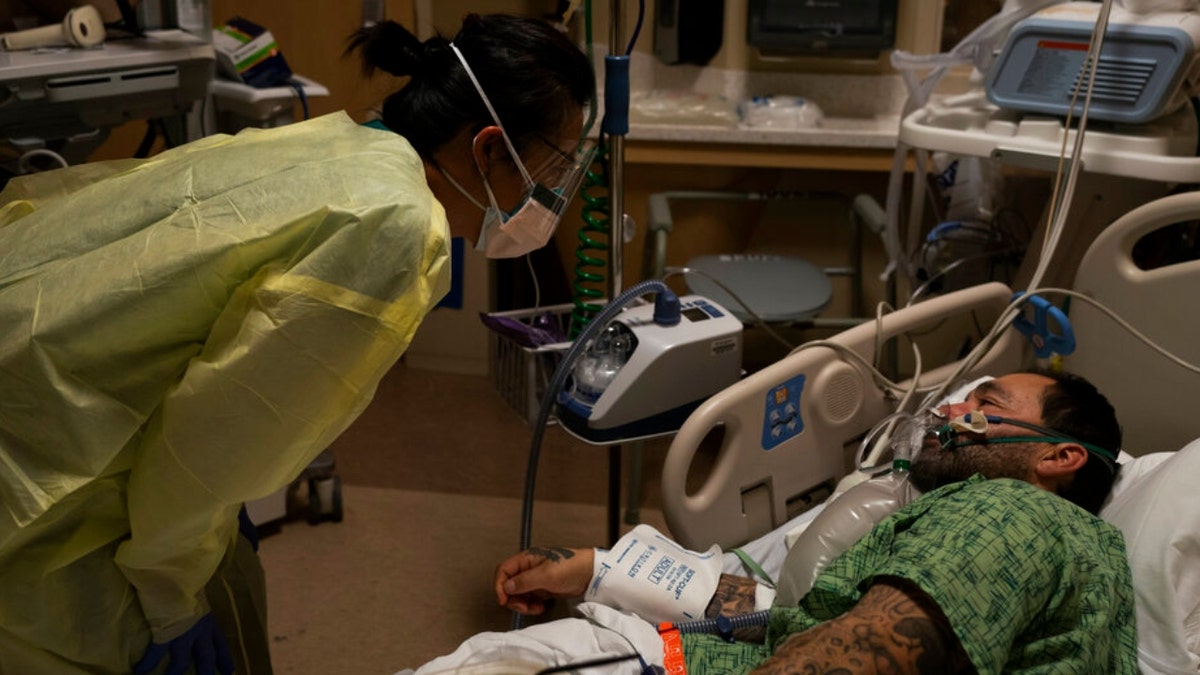 Registered nurse Emily Yu, left, talks to Paul Altamirano, a 50-year-old COVID-19 patient, at Providence Holy Cross Medical Center in Los Angeles, Dec. 13, 2021.