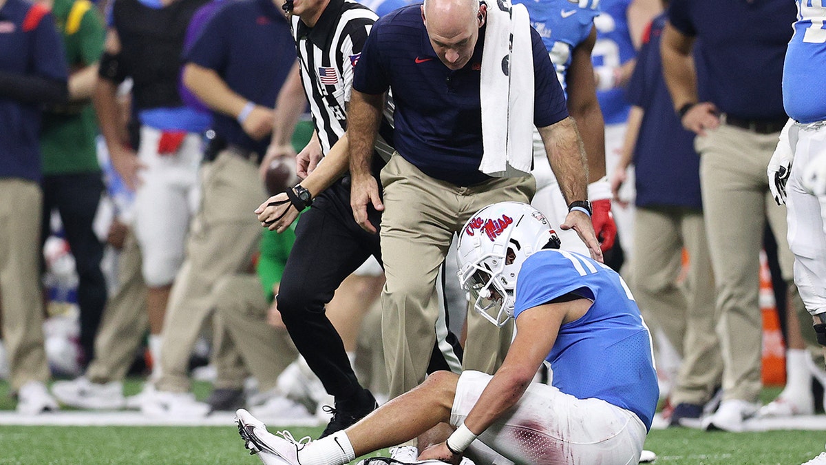 Matt Corral #2 of the Mississippi Rebels is looked over by a trainer after being injured against the Baylor Bears during the first quarter in the Allstate Sugar Bowl at Caesars Superdome on January 01, 2022 in New Orleans, Louisiana.