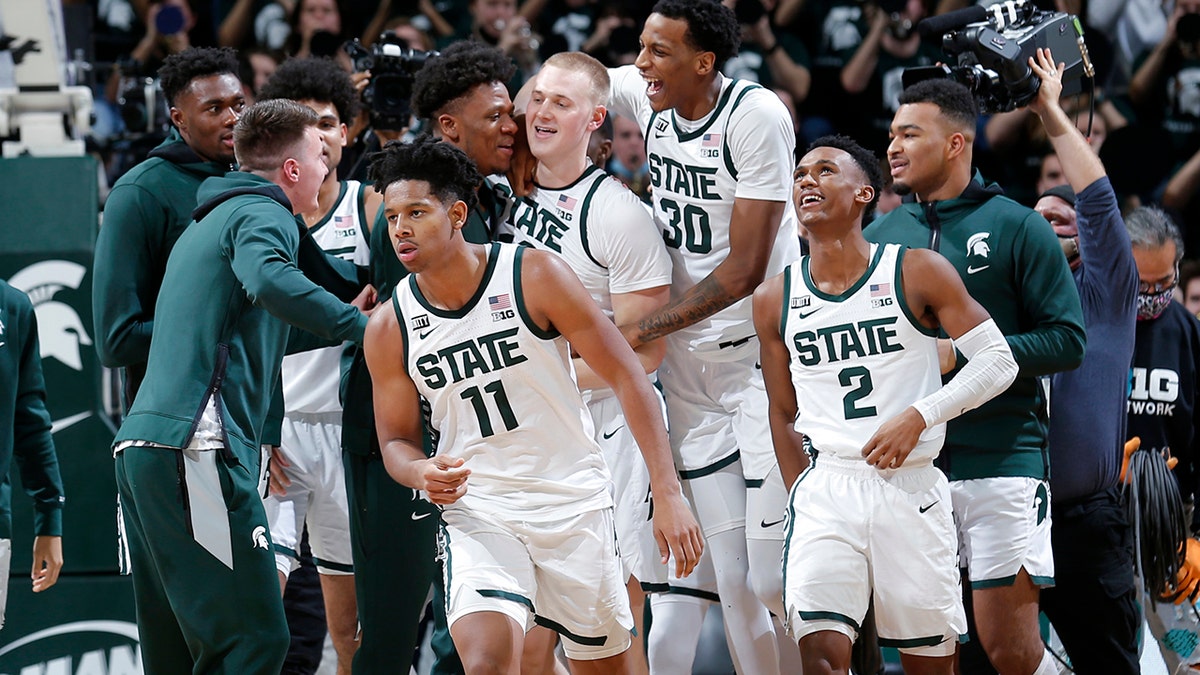 Michigan State players, including A.J. Hoggard (11), Marcus Bingham Jr. (30), Tyson Walker (2) and Joey Hauser, center, celebrate after defeating Minnesota in an NCAA college basketball game, Wednesday, Jan. 12, 2022, in East Lansing, Mich. Michigan State won 71-69.