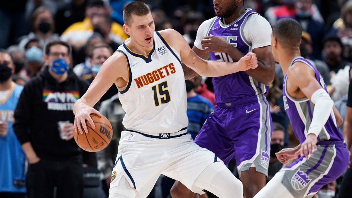 Denver Nuggets center Nikola Jokic, left, is defended by Sacramento Kings center Damian Jones, middle, and guard Tyrese Haliburton during the first half of an NBA basketball game Friday, Jan. 7, 2022, in Denver. 