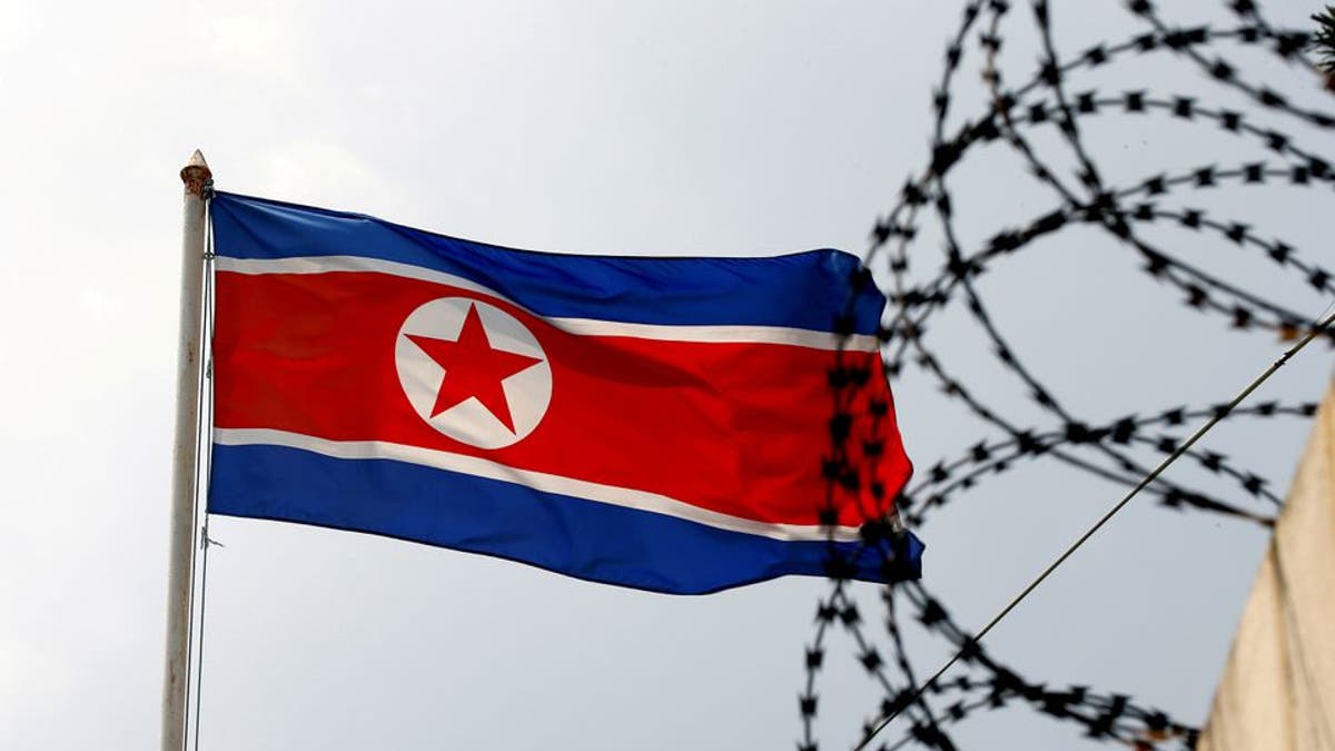 Bandera de Corea del Norte junto a alambre de púas