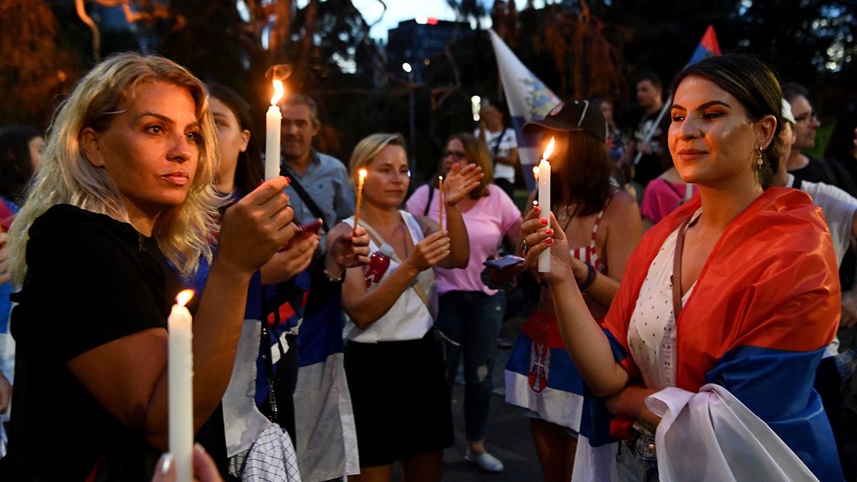 Members of the local Serbian community gather for a vigil outside a hotel where Serbia's tennis champion Novak Djokovic is reported to be staying in Melbourne on January 6, 2022, after Australia said it had cancelled Djokovic's entry visa after having failed to "provide appropriate evidence" of double vaccination or a medical exemption.