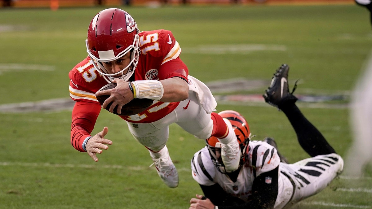 Kansas City Chiefs quarterback Patrick Mahomes (15) dives after running the ball ahead of Cincinnati Bengals defensive end Trey Hendrickson, right, during the second half of the AFC championship NFL football game, Sunday, Jan. 30, 2022, in Kansas City, Missouri.
