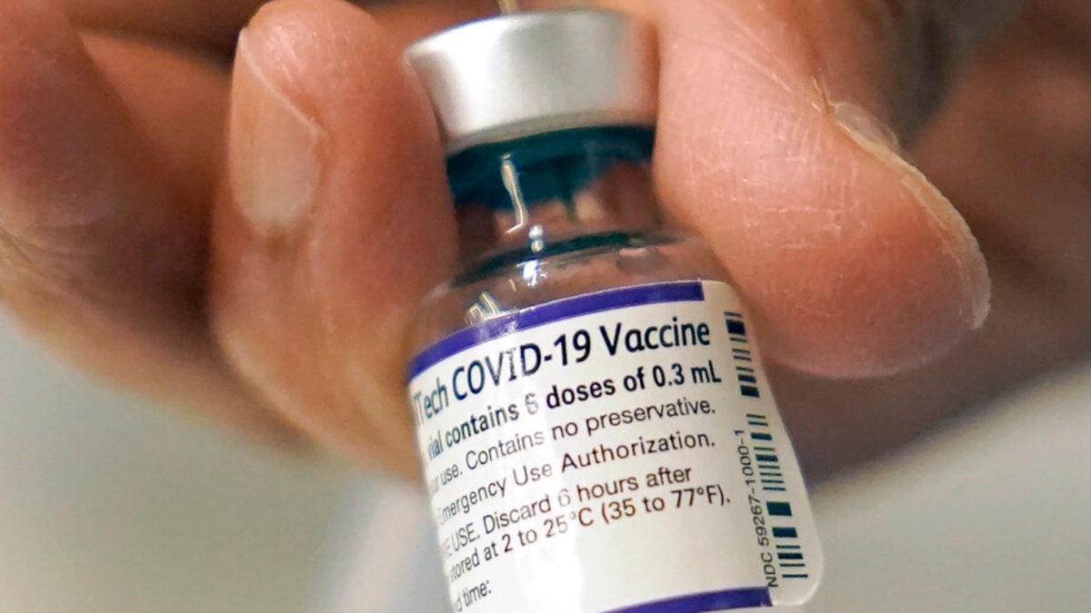 Pfizer COVID-19 vaccine bottle in someone's hand