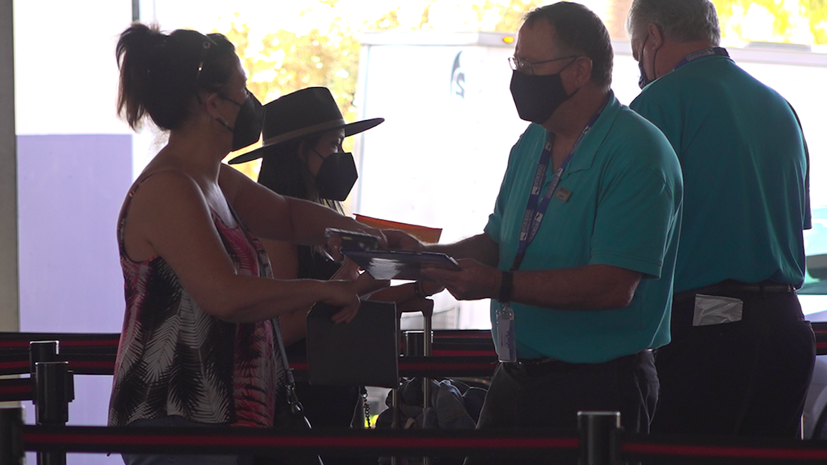 A passenger shows her negative covid-19 test to a crew member before she boards.