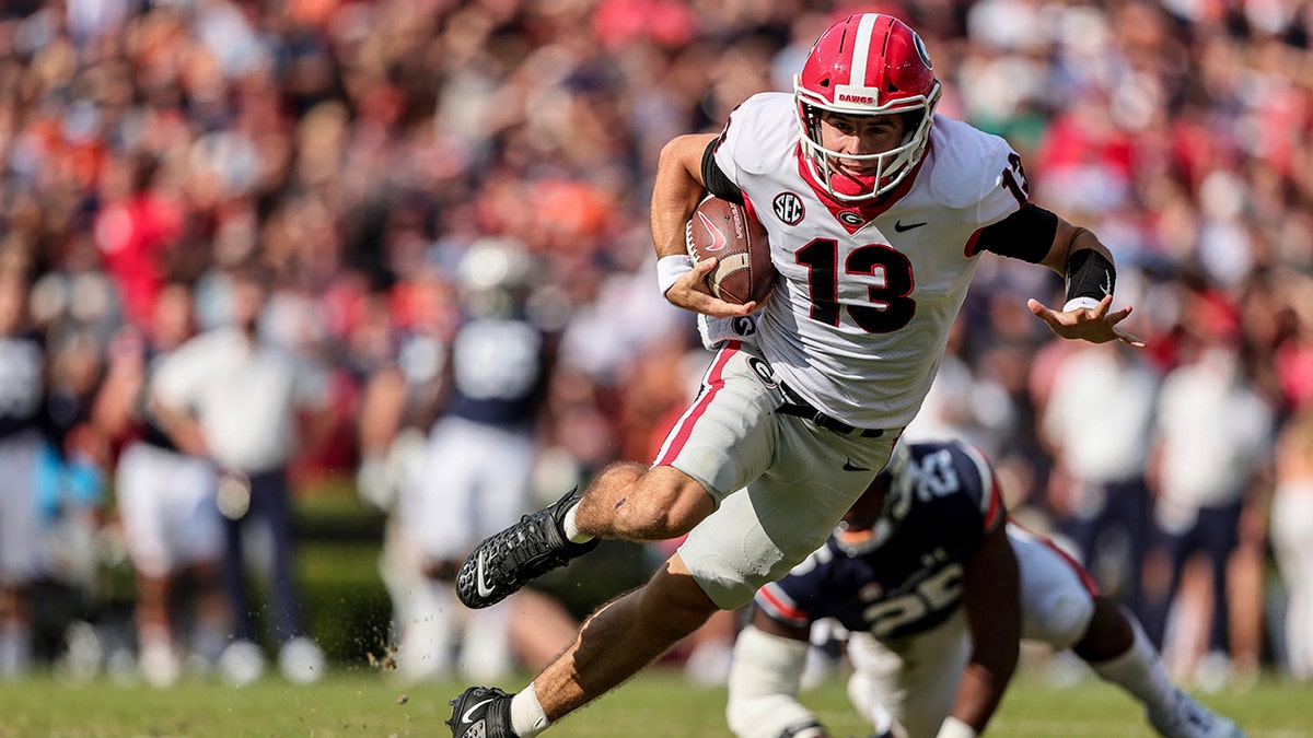 FILE - Georgia quarterback Stetson Bennett (13) carries the ball against Auburn during the first half of an NCAA college football game Saturday, Oct. 9, 2021, in Auburn, Ala. Georgia plays Alabama in the College Football Playoff national championship game on Jan. 10, 2022. 