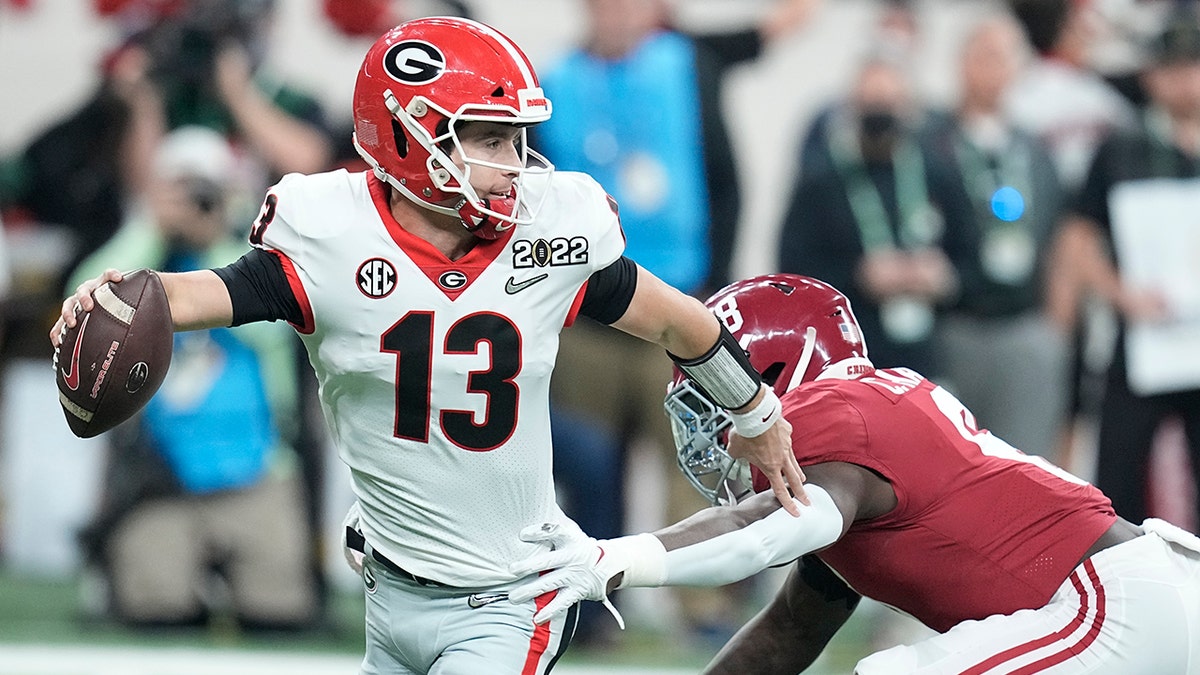 Georgia's Stetson Bennett gets away from Alabama's Christian Harris during the first half of the College Football Playoff championship football game Monday, Jan. 10, 2022, in Indianapolis.