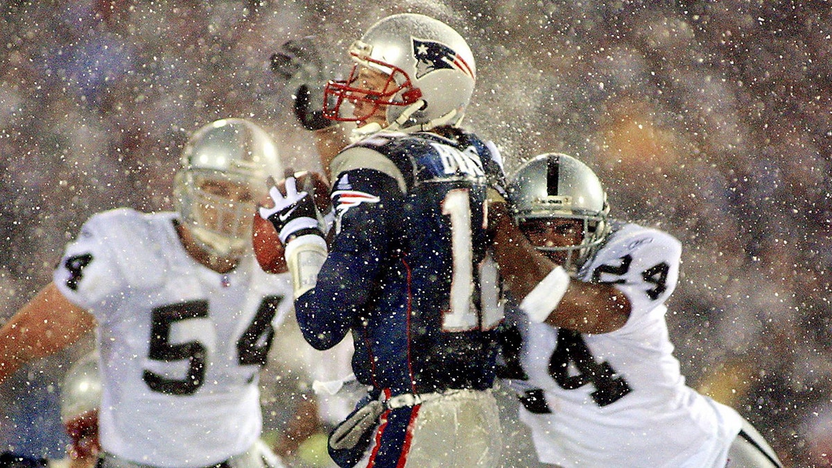 New England Patriots quarterback Tom Brady takes a hit from Charles Woodson of the Oakland Raiders on a pass attempt in the last two minutes of a game in the AFC playoffs Jan. 19, 2002, in Foxboro, Massachusetts.