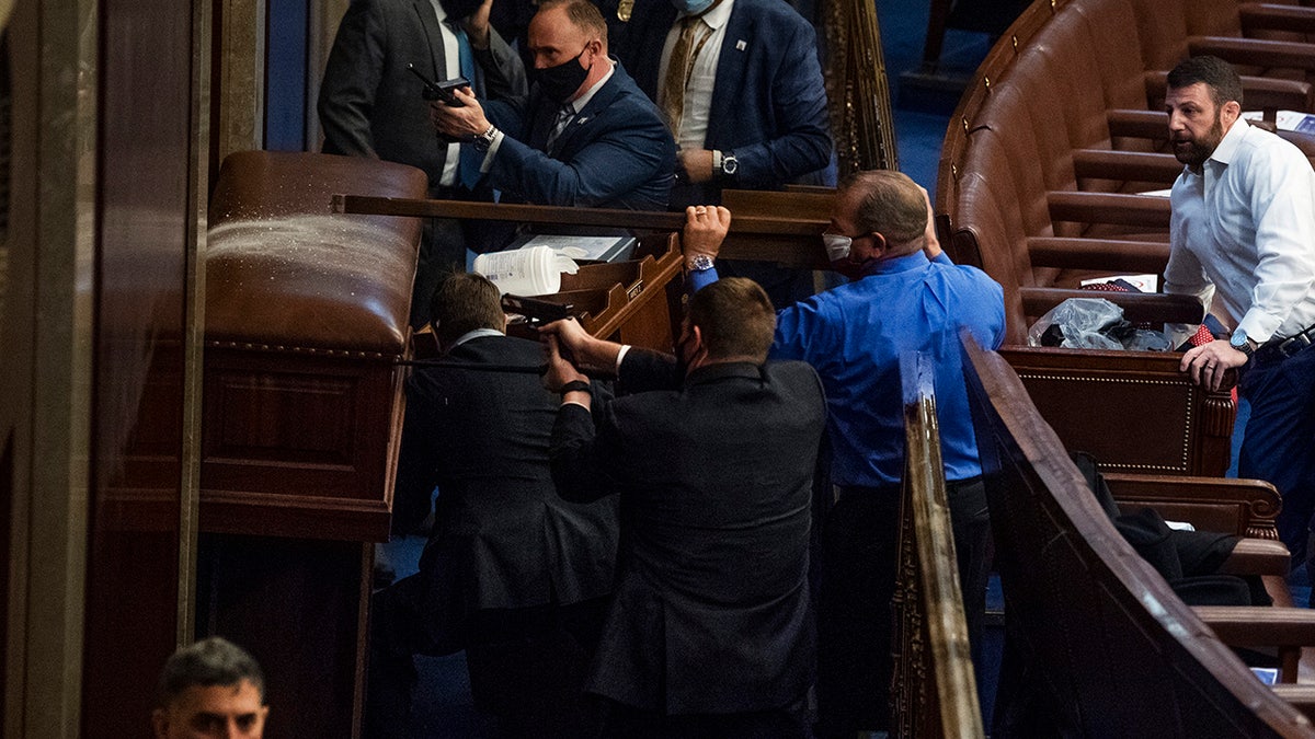 Rep. Troy Nehls, R-Texas, blue shirt, uses a sign to deter rioters as they tried to break into the House chamber to disrupt the joint session of Congress to certify the Electoral College vote Jan. 6, 2021