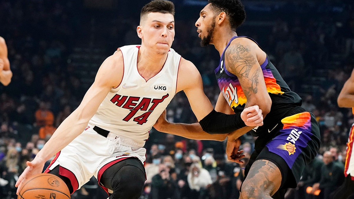 Miami Heat's Tyler Herro (14) drives around Phoenix Suns' Cameron Payne during the first half of an NBA basketball game Saturday, Jan. 8, 2022, in Phoenix.