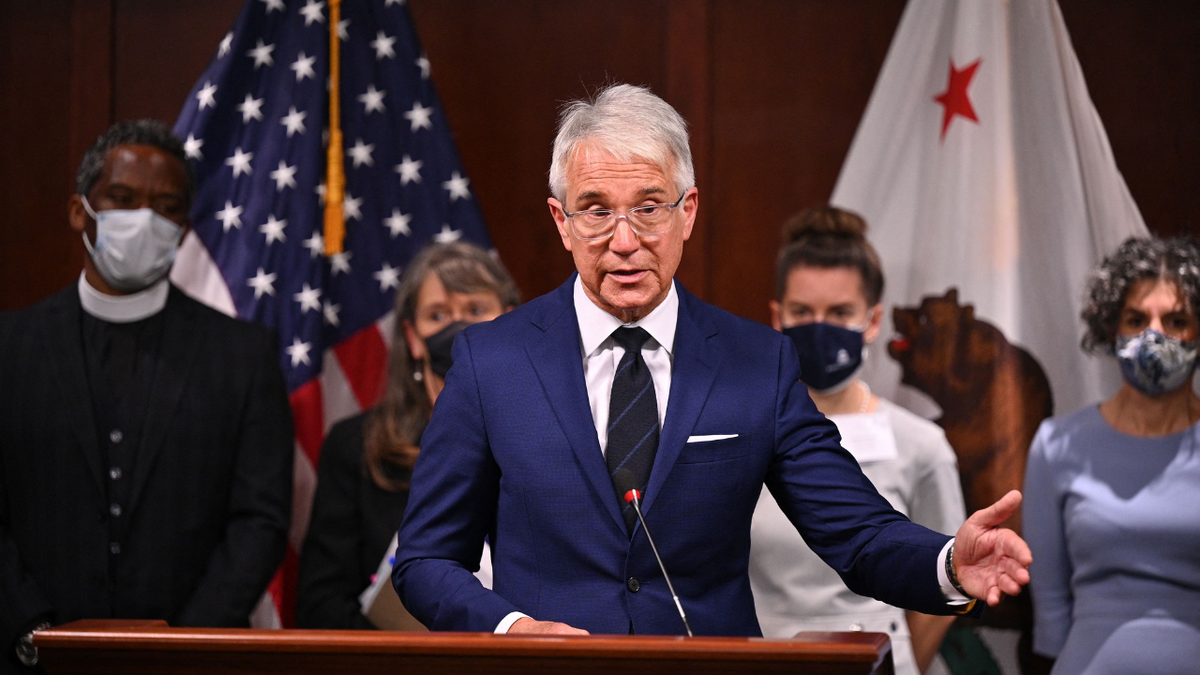 George Gascon in a blue suit stands behind a podium