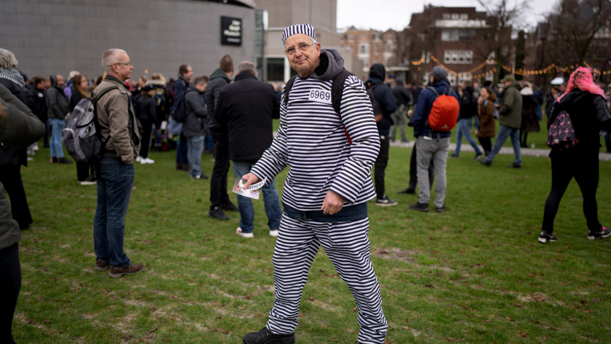 A man wearing a prisoner's suit joined hundreds of people who defied a ban Sunday to gather and protest the Dutch government's coronavirus lockdown measures, in Amsterdam, Netherlands, Sunday, Jan. 2, 2022. (AP Photo/Peter Dejong)