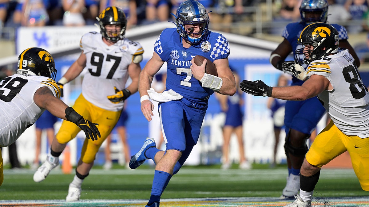 Kentucky quarterback Will Levis (7) scrambles for yardage between Iowa defensive linemen Noah Shannon (99), Zach VanValkenburg (97) and Logan Lee (85) during the second half of the Citrus Bowl Saturday, Jan. 1, 2022, in Orlando, Fla.