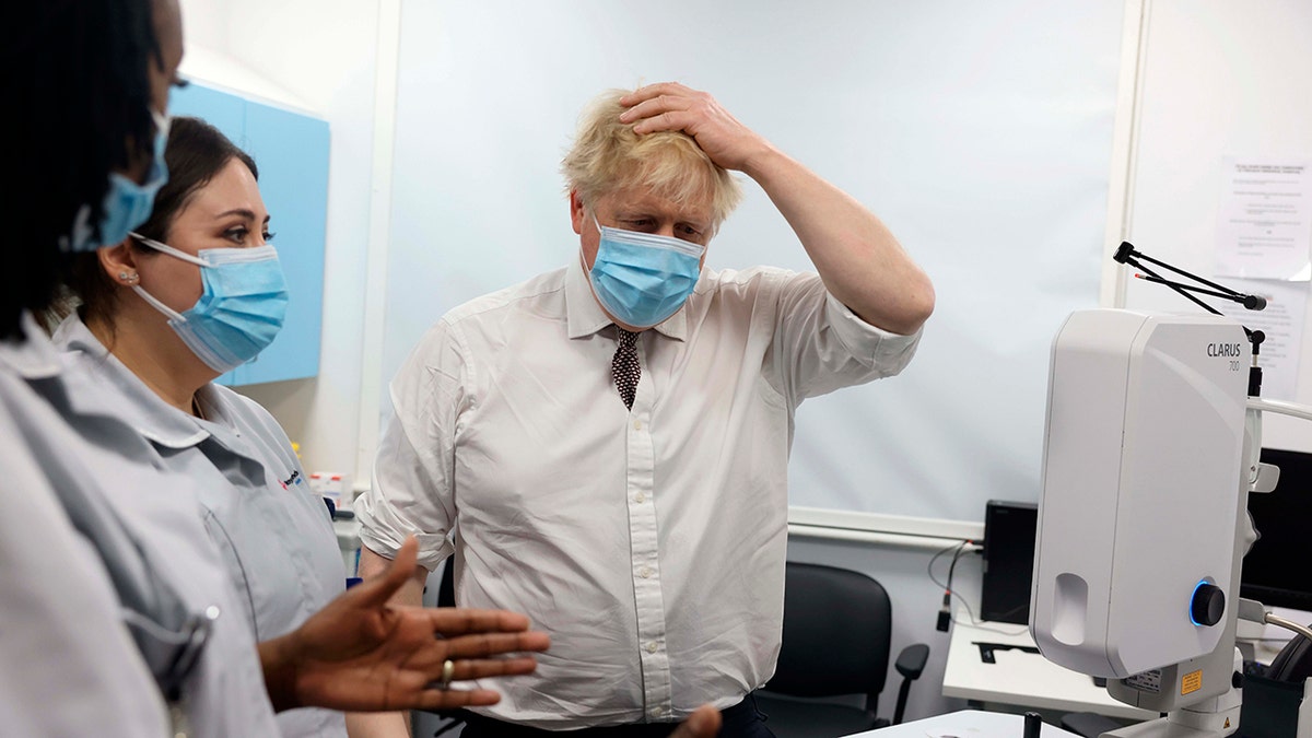 Britain's Prime Minister Boris Johnson, center, gestures during a visit to Finchley Memorial Hospital in North London, Tuesday, Jan. 18, 2022. 
