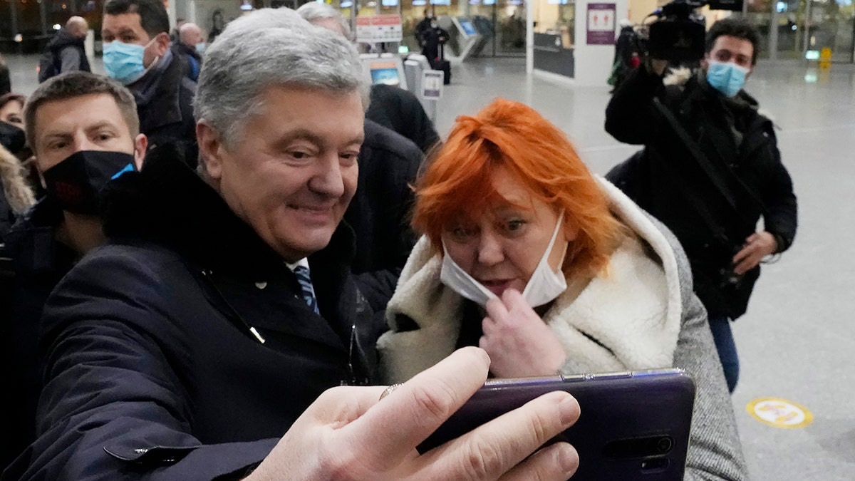 Former Ukrainian President Petro Poroshenko, left, poses for a selfie with a Ukrainian supporter at Warsaw's international airport before boarding a flight to Kyiv, Ukraine, on Monday, Jan. 17, 2022. 