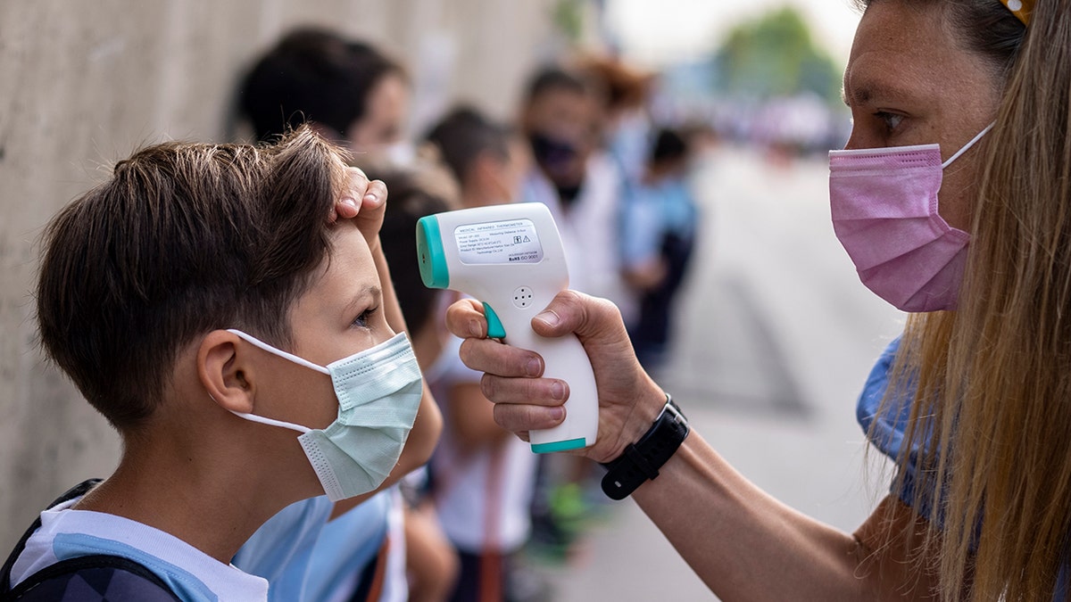  A teacher wearing a face mask to protect against the spread of coronavirus checks the temperature of her student at Maestro Padilla school as the new school year begins in Madrid, Sept. 7, 2021. 