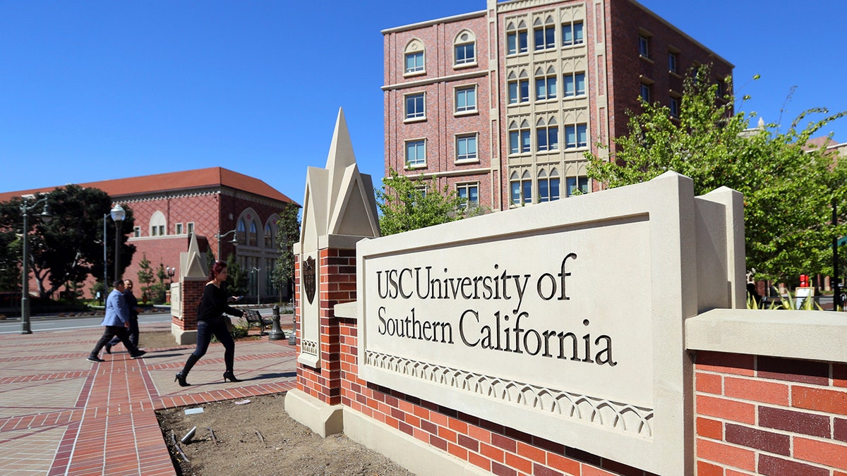 In this March 12, 2019, file photo people walk at the University Village area of the University of Southern California in Los Angeles.