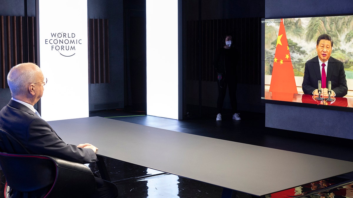 German Klaus Schwab, left, founder and executive Chairman of the World Economic Forum (WEF), listens to Chinese President Xi Jinping displayed in a screen during the opening Davos Agenda 2022, in Cologny near Geneva, Switzerland, Monday, Jan. 17, 2022.