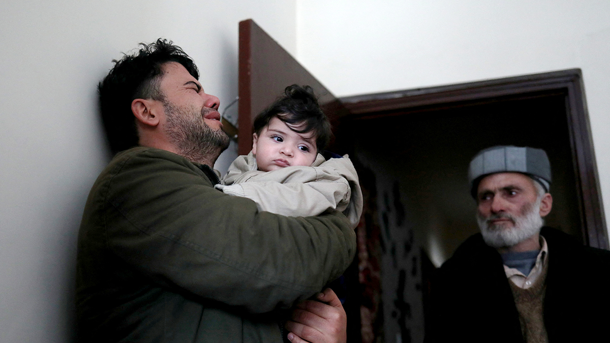 Hamid Safi, a 29-year-old taxi driver who had found baby Sohail Ahmadi in the airport, cries as he holds Sohail before handing him over to his grandfather Mohammad Qasem Razawi in Kabul, Afghanistan, January 8, 2022. Picture taken January 8, 2022. REUTERS/Ali Khara