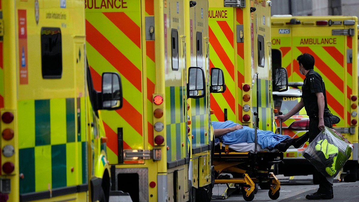 A patient is pushed on a trolley after arriving in an ambulance outside the Royal London Hospital in the Whitechapel area of east London, Jan. 6, 2022.