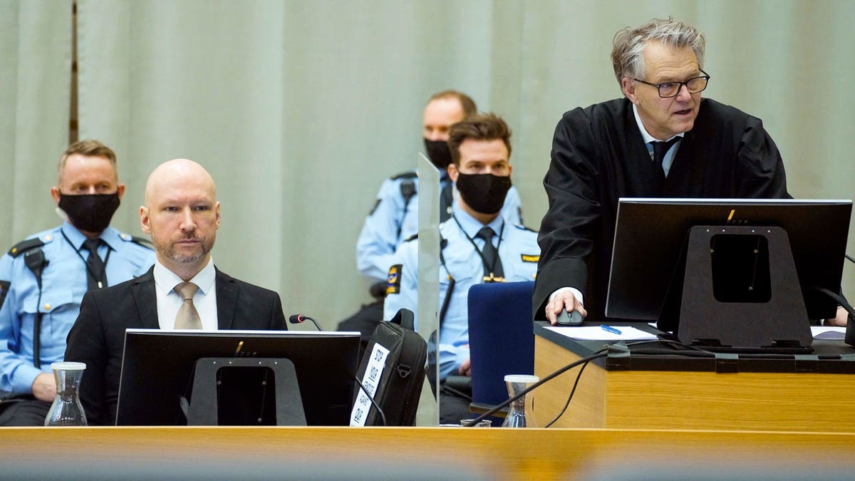 Convicted mass murderer Anders Behring Breivik, left, and defense lawyer Oystein Storrvik participate in the makeshift courtroom in Skien prison on the third day of the trial, where he is requesting release on parole, in Skien, Norway, Jan. 20, 2022.