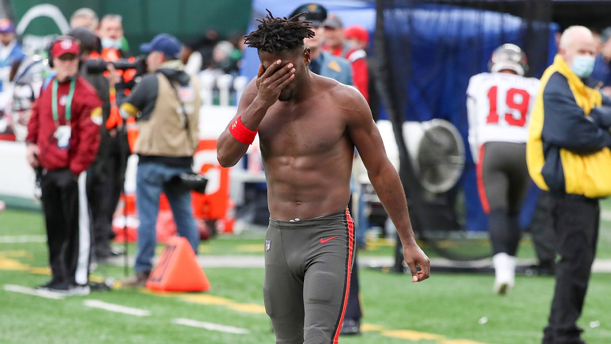 Tampa Bay Buccaneers wide receiver Antonio Brown wipes his face as he leaves the field after throwing his equipment into the stands while his team is on offense during the third quarter of an NFL football game against the New York Jets, Sunday, Jan. 2, 2022, in East Rutherford, New Jersey.